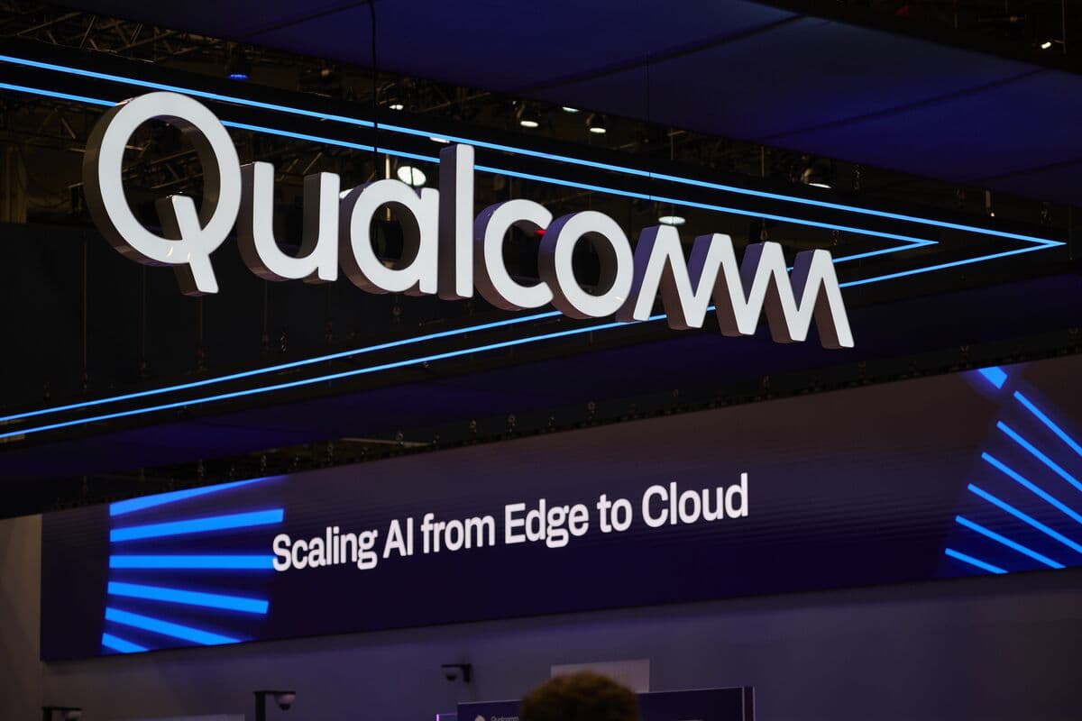 Qualcomm execs and Modular's Chris Lattner shake hands over a deal, with AI code and Mojo language graphics on…