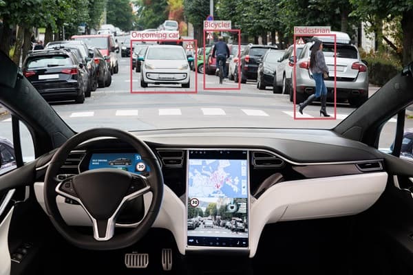 A Waymo self-driving minivan with roof sensors navigates a city street, surrounded by other cars and pedestrians…