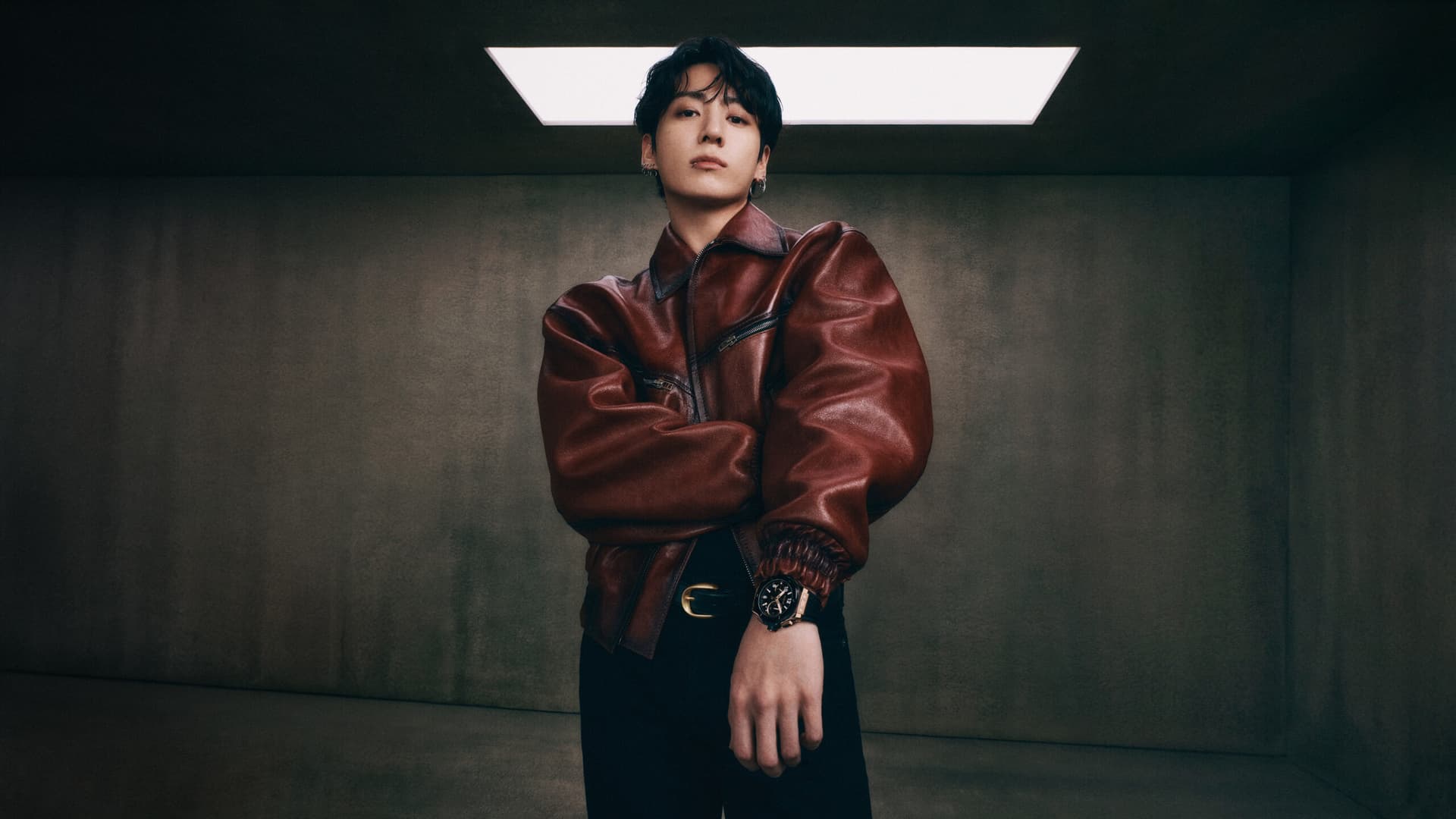 BTS member Jung Kook wears a Graff diamond necklace and bracelet, posing against a dark background with subtle lighting