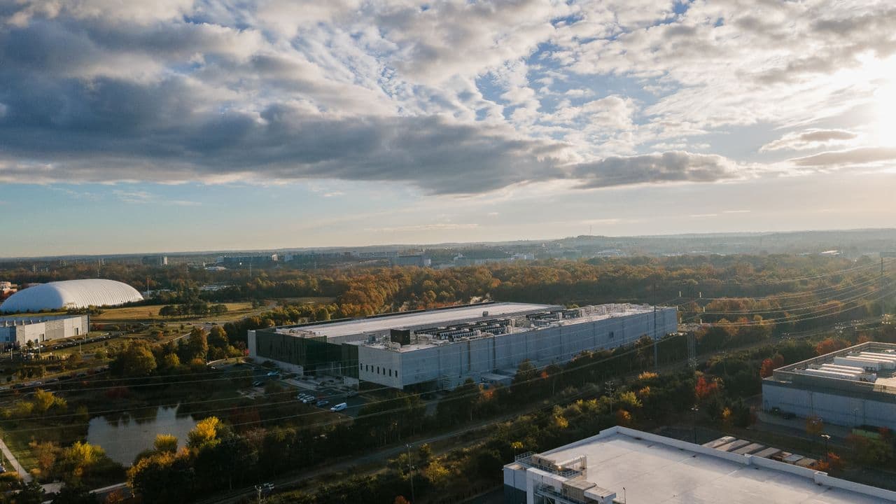 Aerial view of a massive data center construction site in Louisiana with new server buildings, cooling towers, and…
