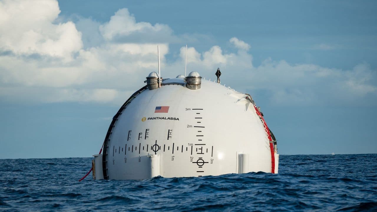 Massive floating platform with wave energy converters and data center modules on ocean surface under partly cloudy sky