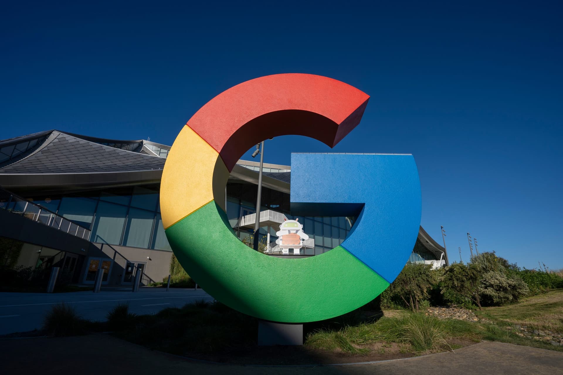 A graph on a monitor displays declining stock prices for Micron, Samsung, and SK Hynix, with a Google AI research…