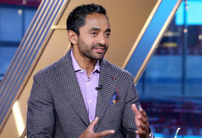 Chamath Palihapitiya gestures while speaking, with a backdrop of a rocket launch and digital network lines…