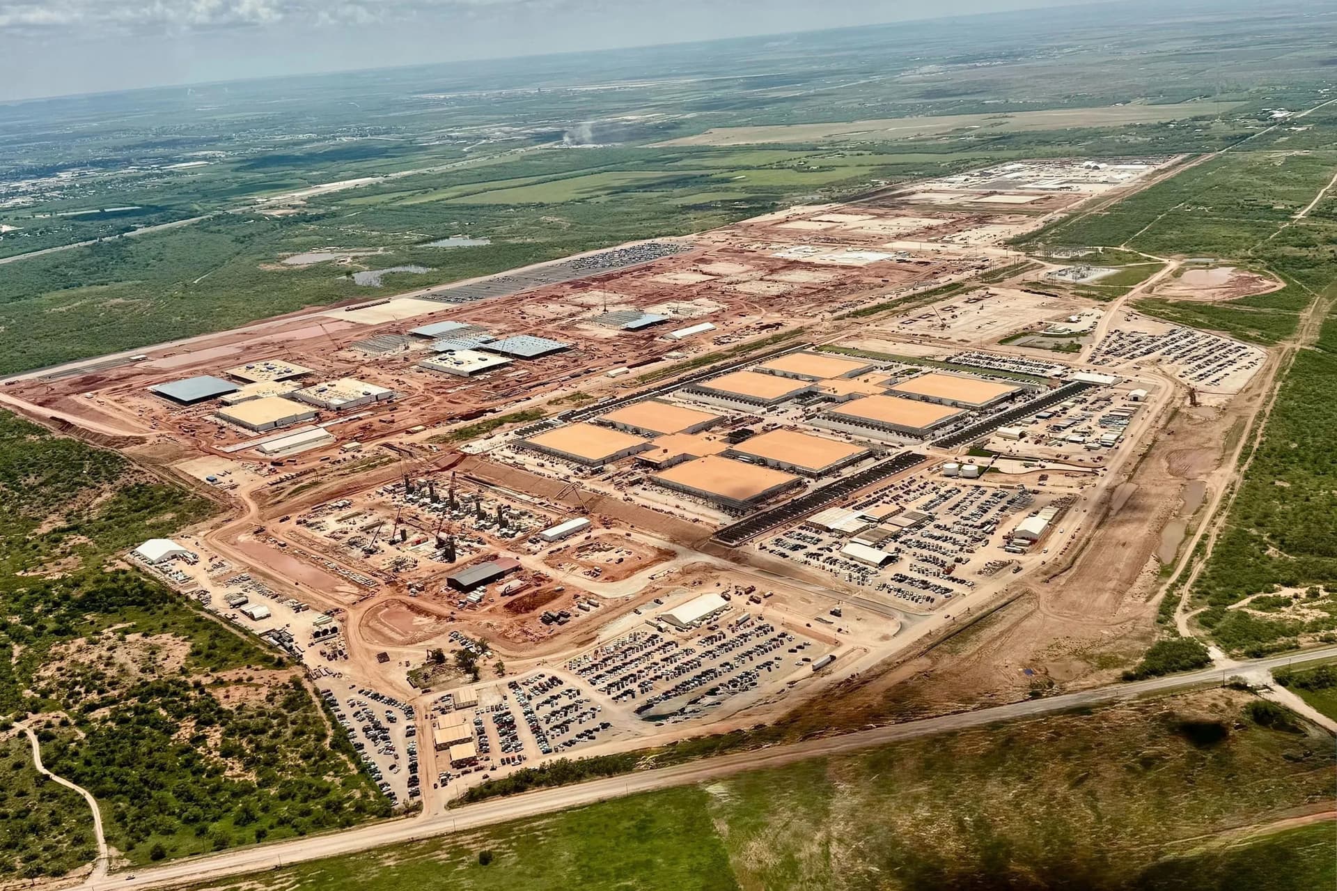 A large data center construction site in Abilene, Texas, with cranes, steel framework, and dirt roads under a clear…