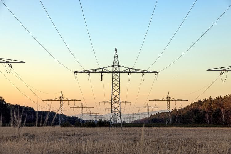 An electrical grid control center with large screens displaying power network maps and data, engineers monitoring…
