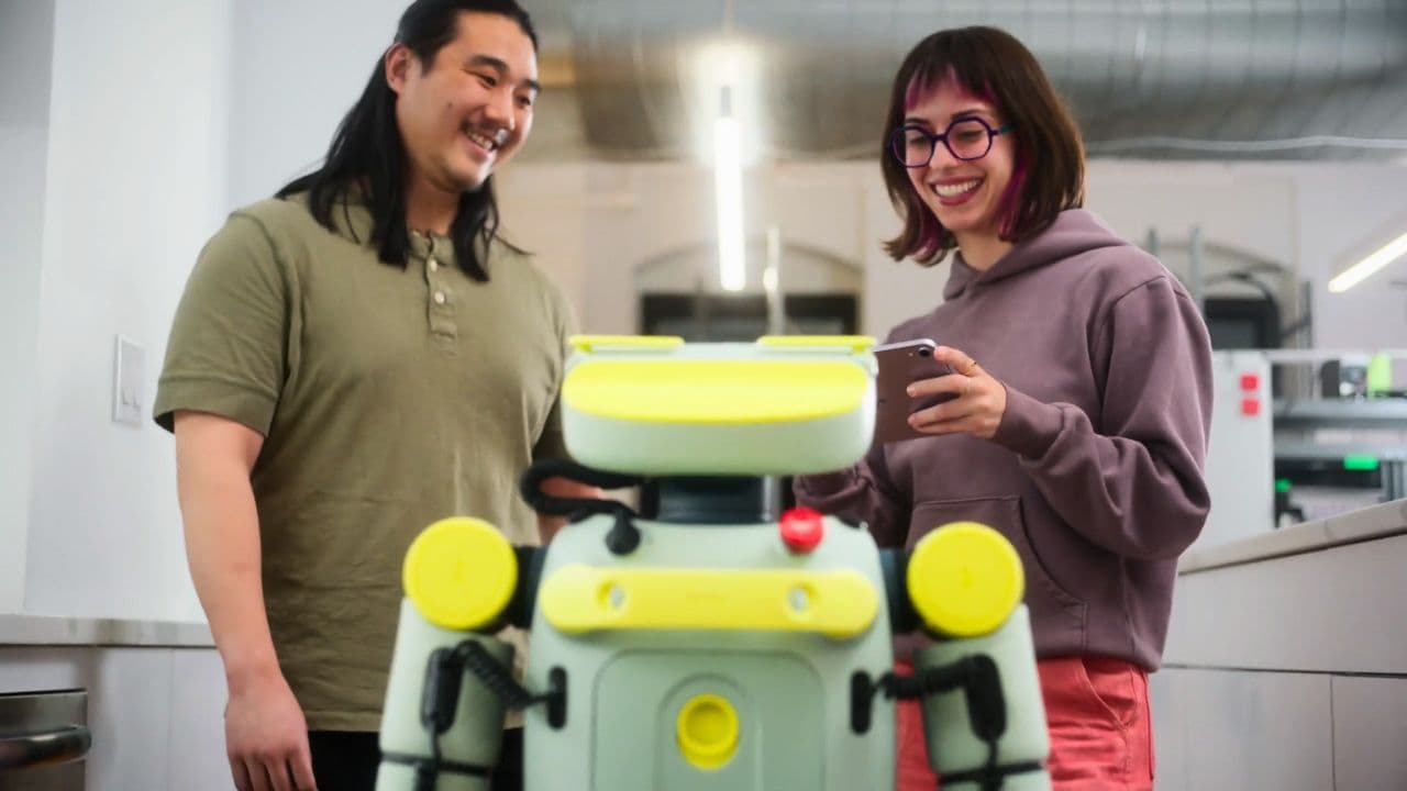 Small green humanoid robot with round head and jointed arms grips a box on a warehouse shelf, surrounded by…