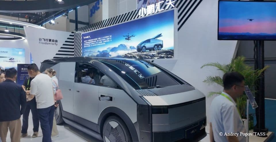 A 6x6 ground vehicle with a detachable two-seat eVTOL aircraft mounted on its back, displayed at a tech event