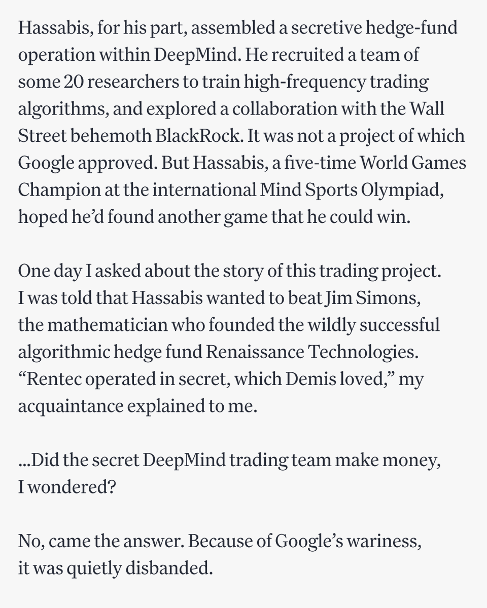 A group of about 20 researchers huddle around multiple computer monitors displaying trading charts and stock data…