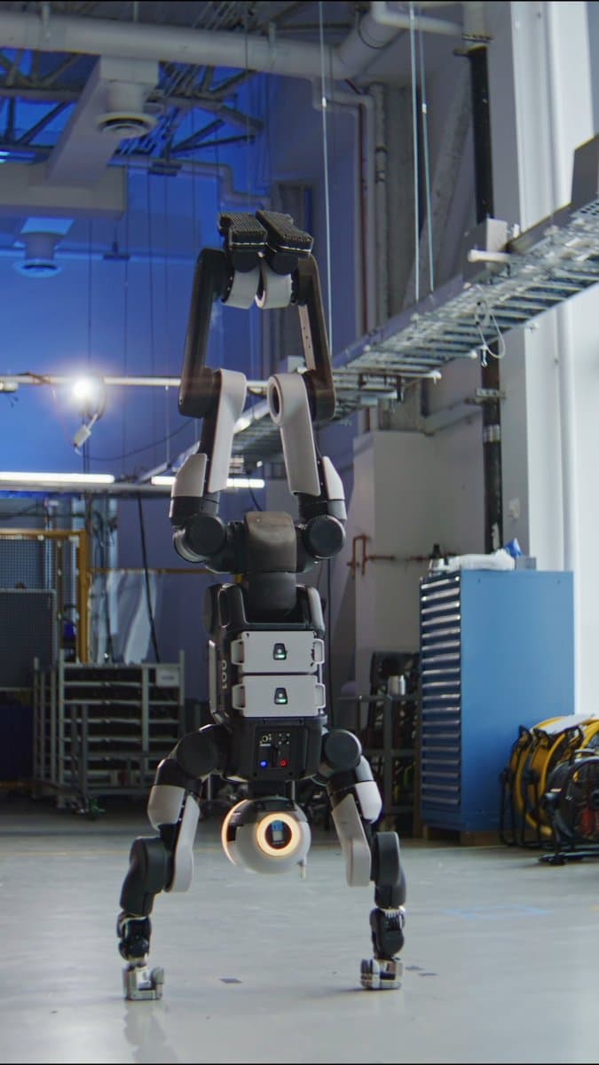 Humanoid robot Atlas balances on its arms and spins its torso in a lab, with visible hand jitter showing real-time…