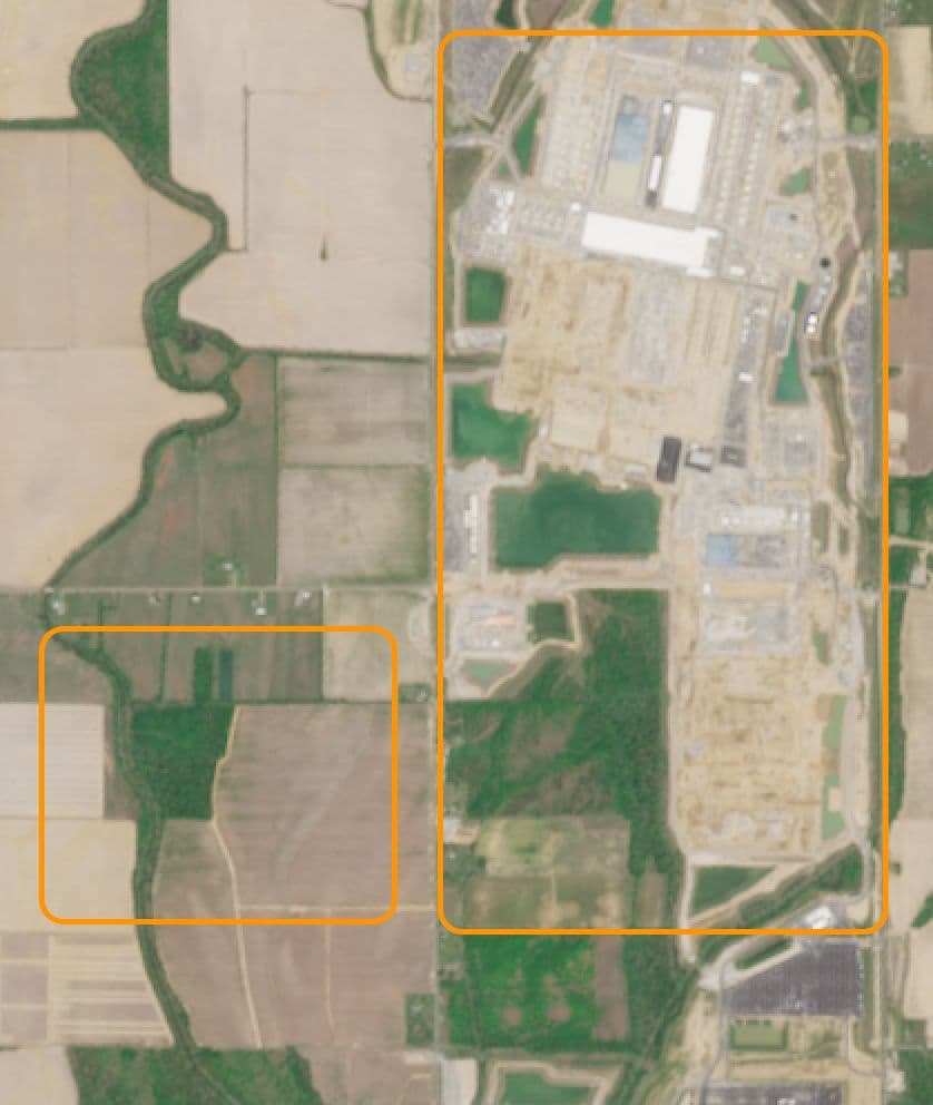 Aerial view of a sprawling datacenter complex under construction on vacant rural land, with excavators and cranes…