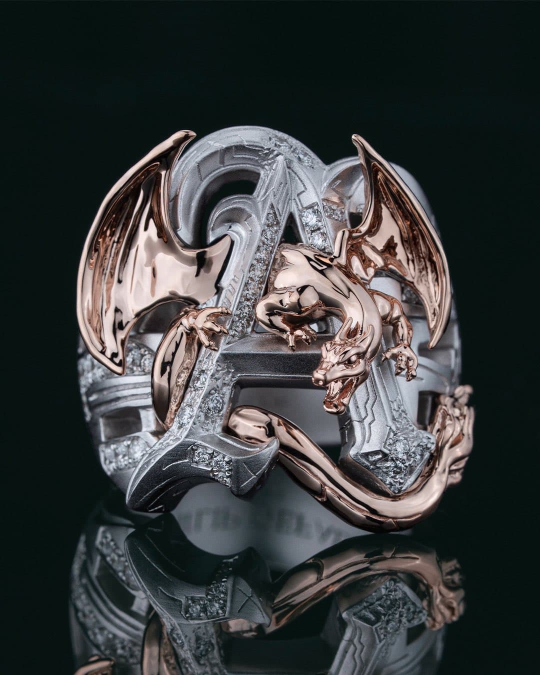 A shiny 18K gold ring shaped like the Pokémon Charizard, with detailed wings and fiery features, displayed on a dark…