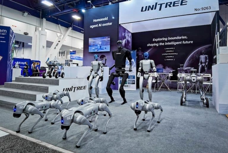 Unitree humanoid robot standing upright with articulated joints, surrounded by engineers in a lab adjusting its…