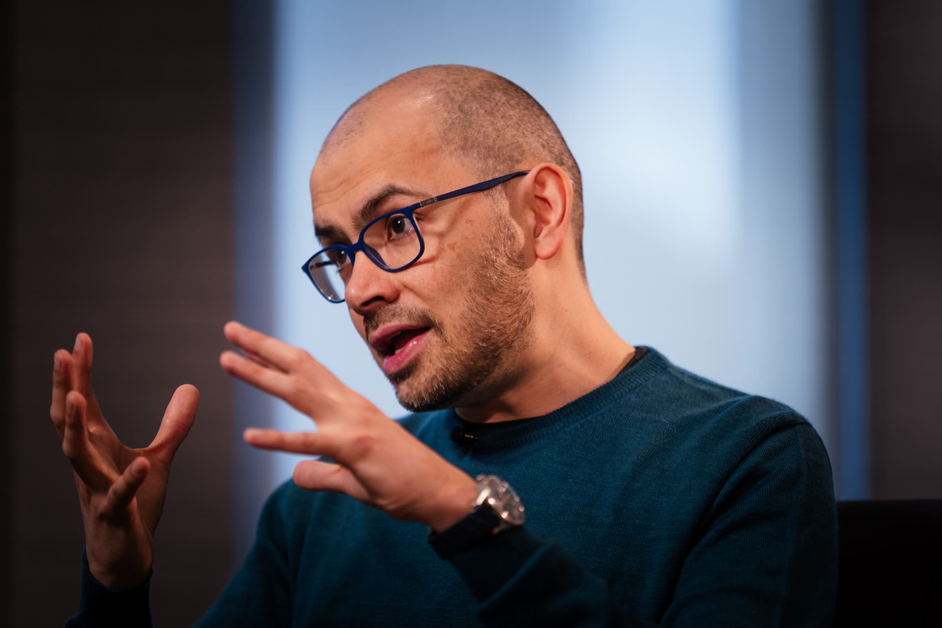 Demis Hassabis speaking at a tech conference, gesturing as he describes how AI tools empower young founders to…