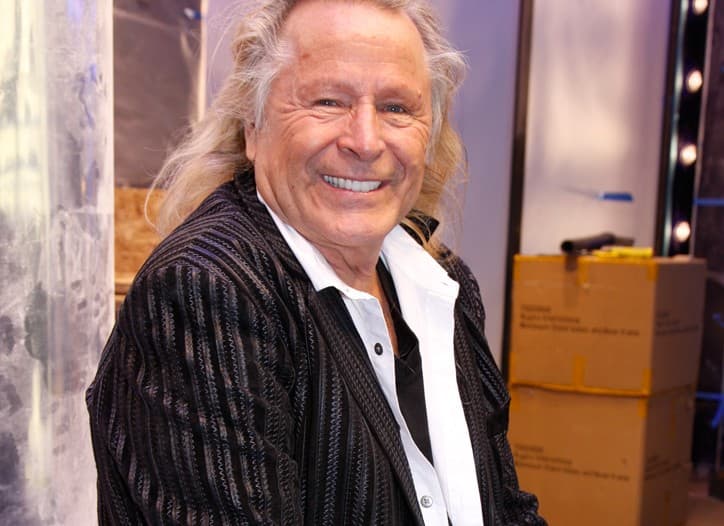 A gray-haired Peter Nygard in a suit stands in a courtroom, looking down, as a verdict is read in his Montreal sex…
