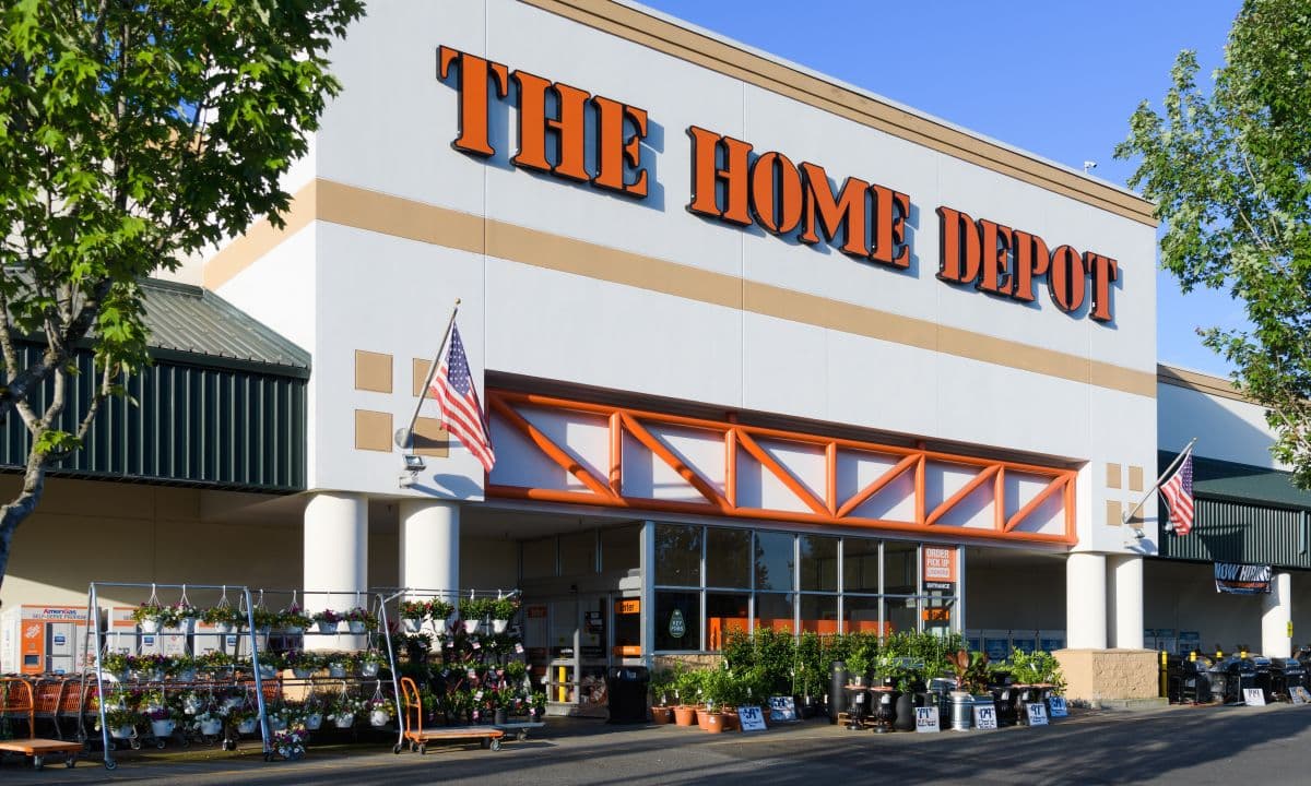 A Home Depot store aisle with a manager in a hard hat consulting a tablet, surrounded by AI data visualizations and…