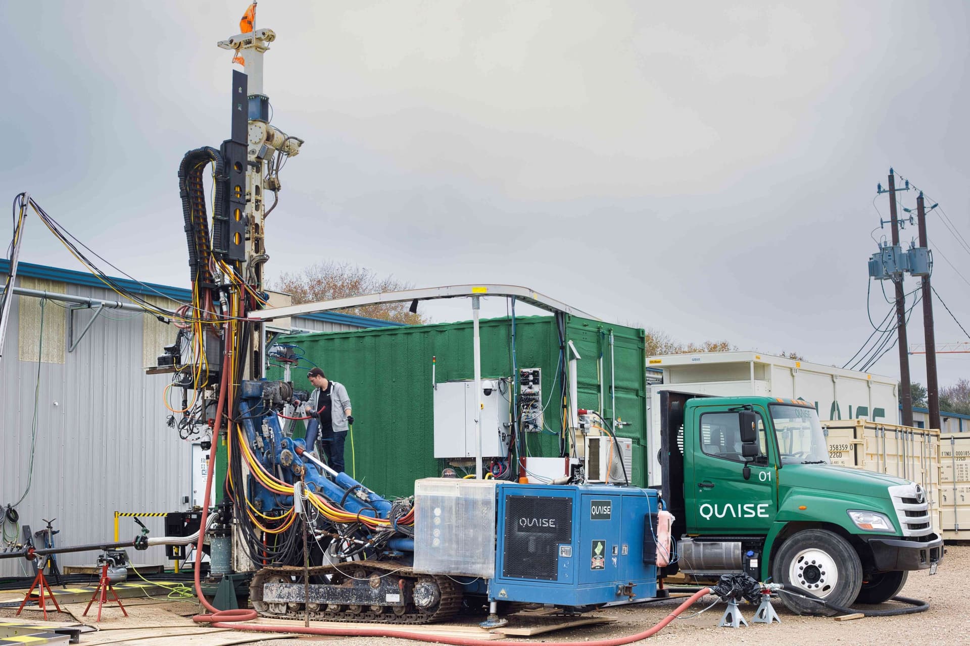 Industrial drilling rig on a test site with workers and equipment under a clear sky, representing Quaise Energy's…