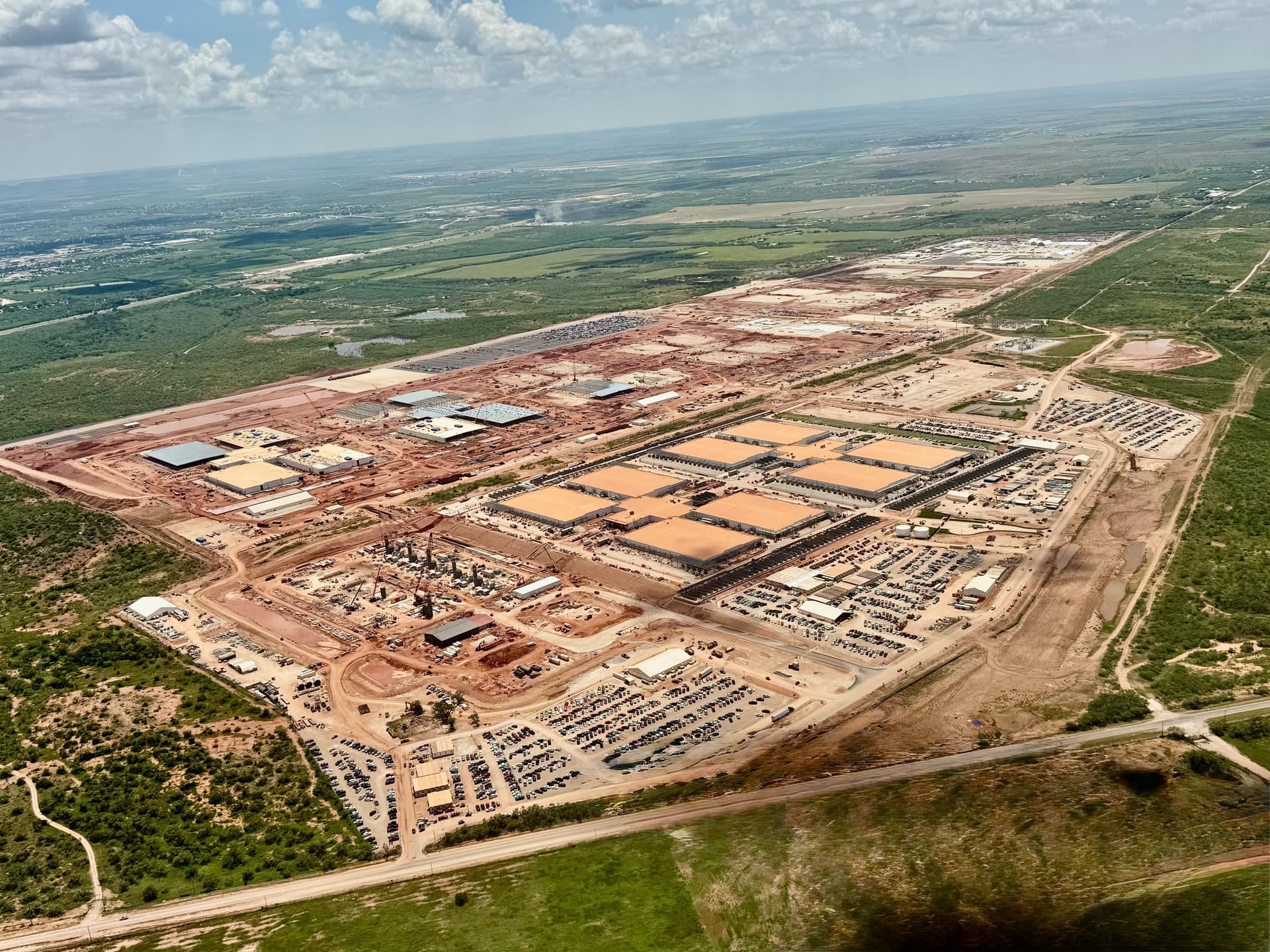 Construction vehicles and workers at a massive Texas construction site with cranes and partially built data center…