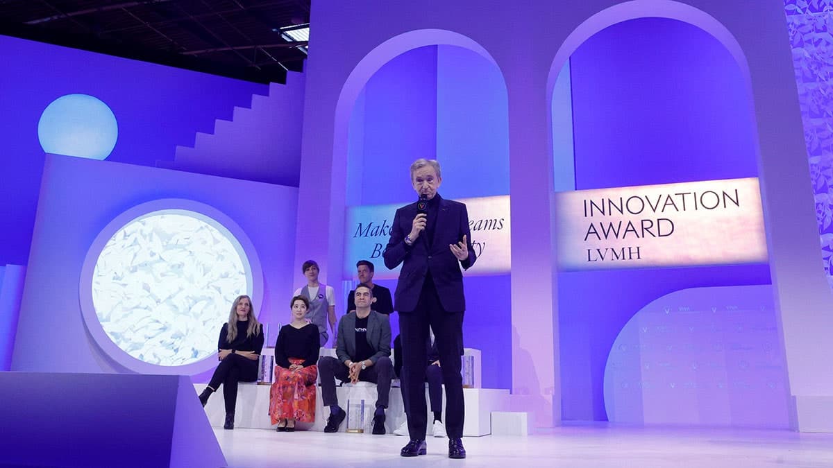 LVMH executive smiling at a tech event, investing in a generative AI startup for virtual try-on technology in luxury…