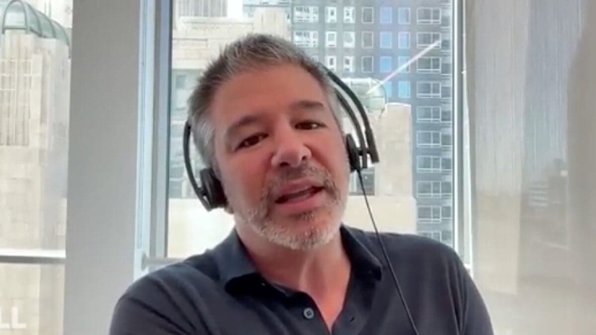 Travis Kalanick speaks on the All-In podcast set, gesturing while praising Tesla as the leading force in physical AI…