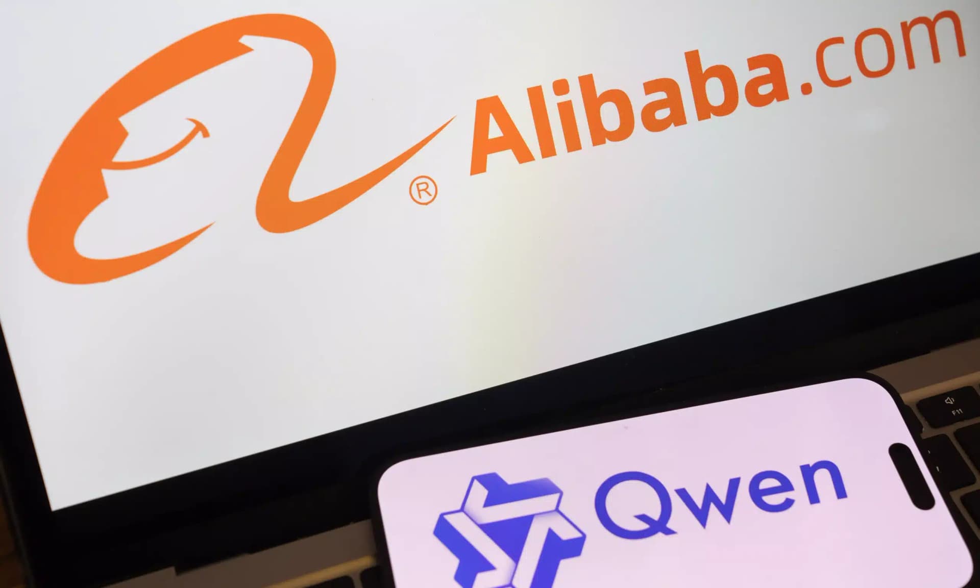 Alibaba Qwen team members gathered around monitors displaying code and AI model architecture diagrams, with a large…