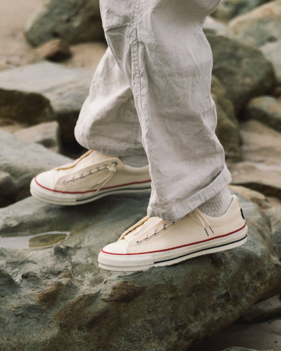 White leather Converse All Star sneaker with a side zipper closure, displayed on a clean surface with soft studio…