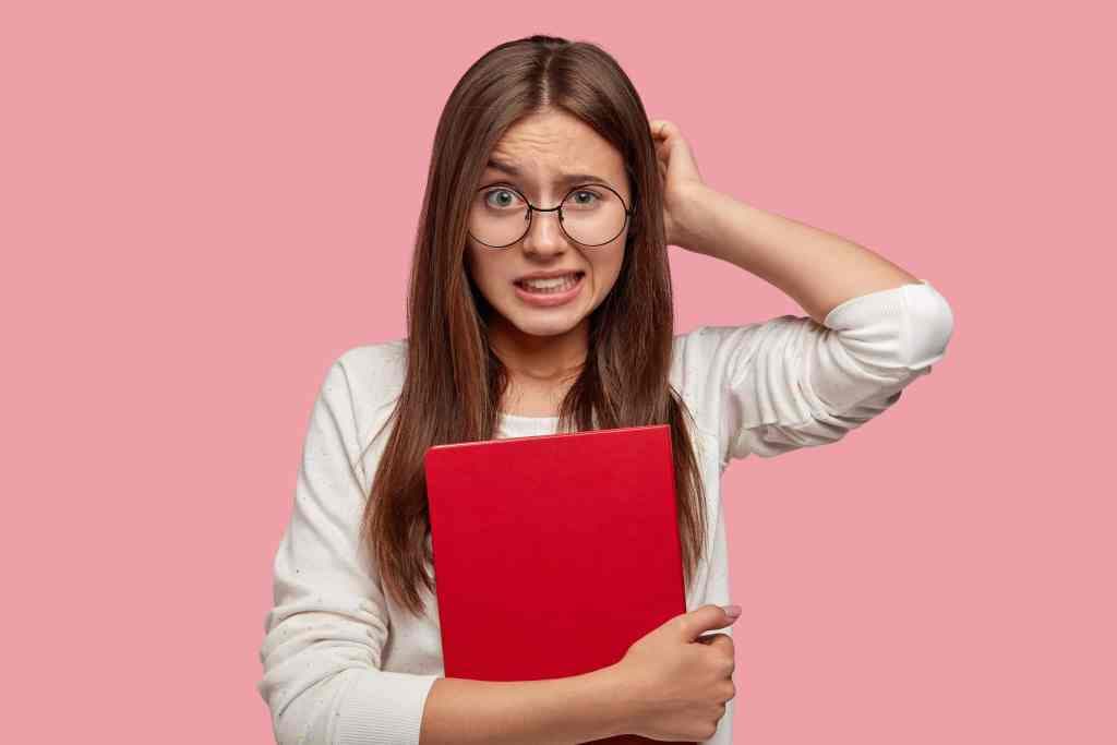 A student scratching head in confusion while studying, holding a red exercise book, illustrating the luxury sector's…