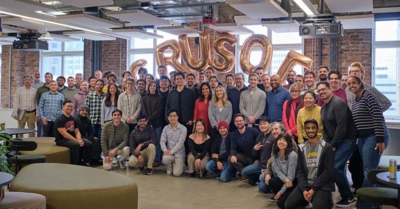 Crusoe team members standing in front of a modular data center structure, surrounded by computing equipment and…