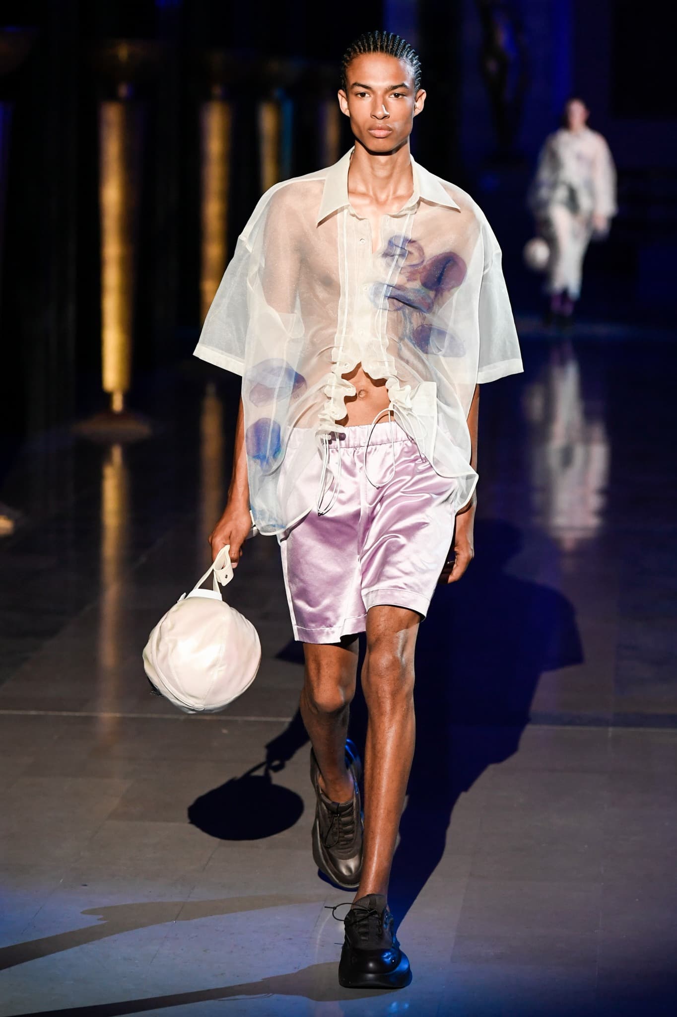 Actor François Arnaud in a sheer shirt at a fashion event, spotlighting male transparency in a 2026 retrospective