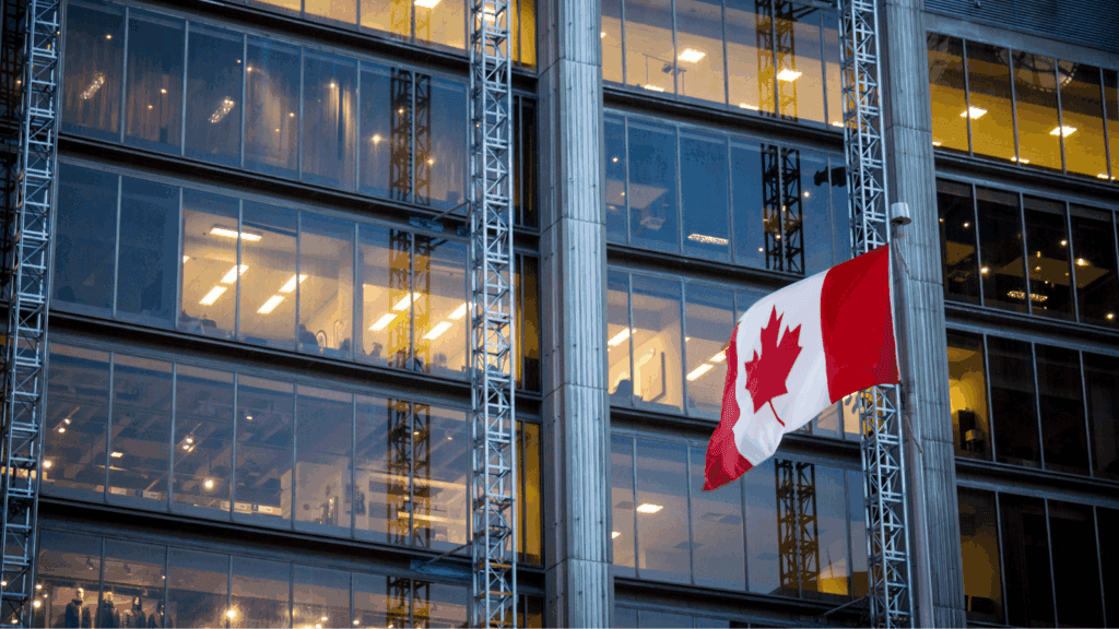 Two executives shake hands in a modern office, with a Bell Canada logo and a Cohere logo visible on a screen behind…